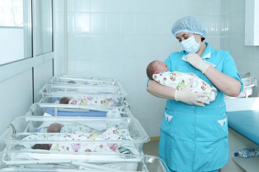Медсестра держит новорожденного на руках