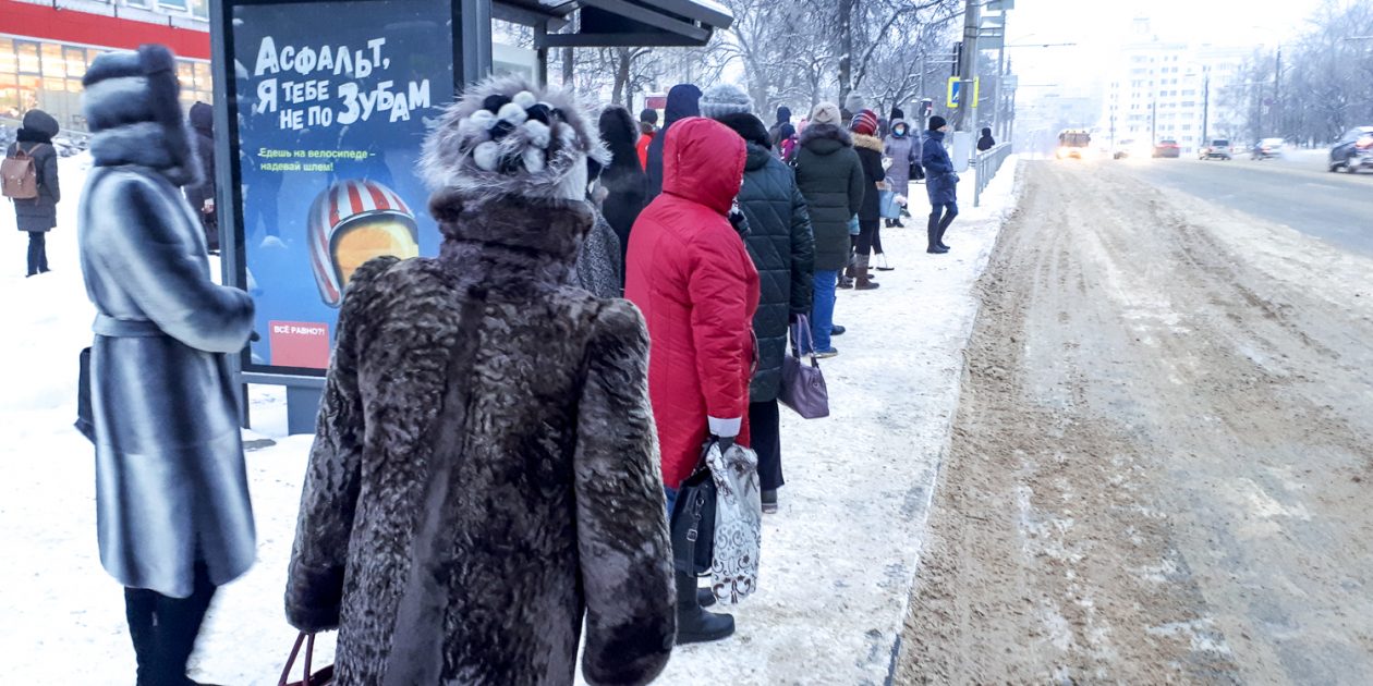 Люди в мороз ждут автобуса на остановке